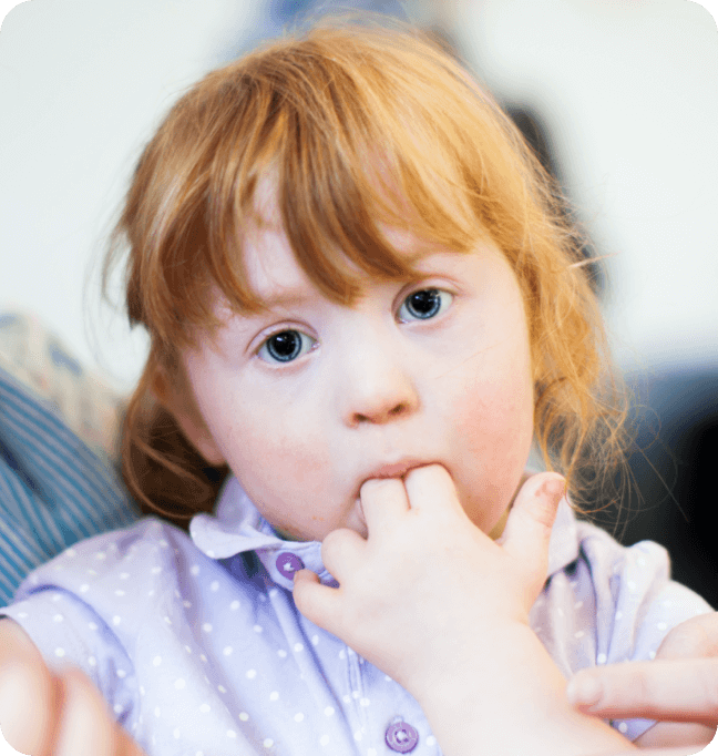 A girl with her fingers in her mouth.
