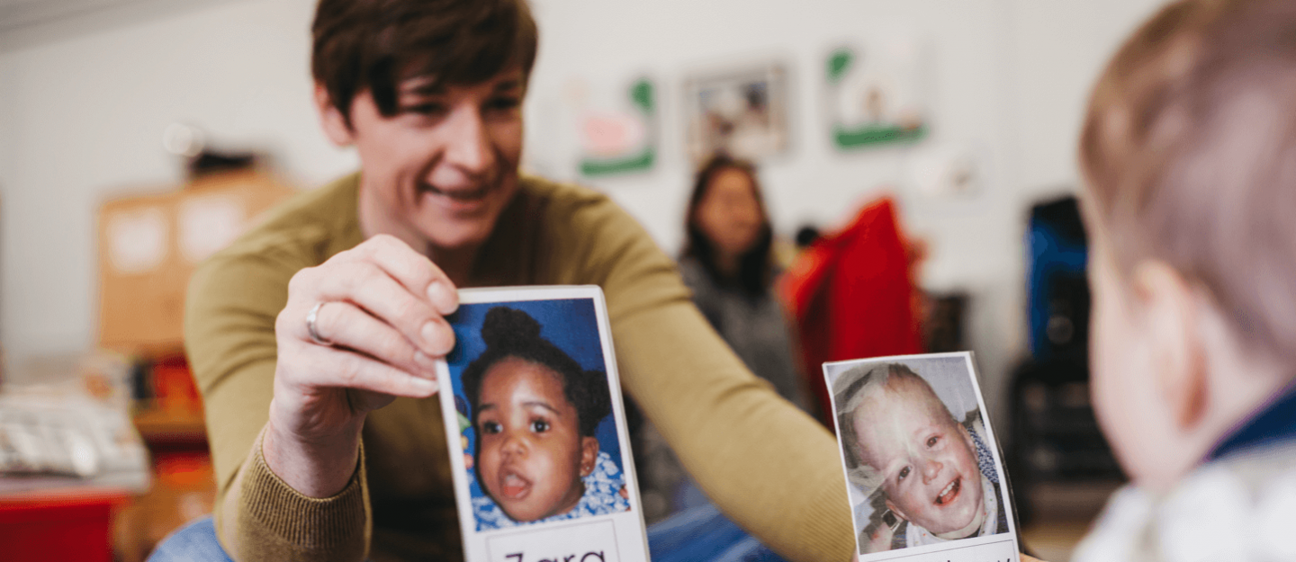 A child looking at 2 images of children's faces on polaroid pictures.
